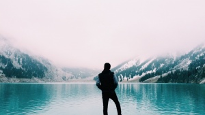 Um homem admirando um lago azul.