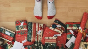 Uma pessoa com meias ao lado de presentes de Natal.