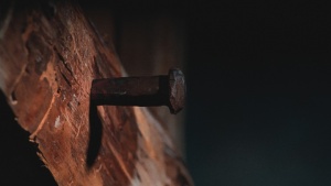 Uma antiga estaca de metal pregada a uma viga de madeira.
