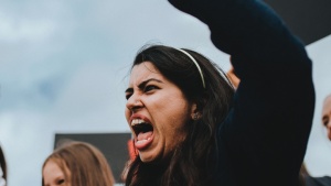 Uma mulher furiosa gritando com o punho no ar.