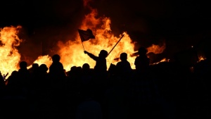 Pessoas em um tumulto queimando itens.