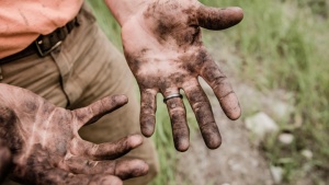 Homem com as mãos sujas pelo trabalho na terra.