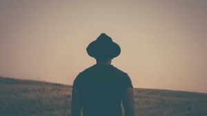 Um homem de chapéu olhando para um campo gramado.