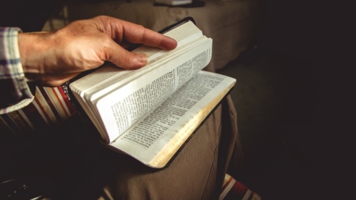 Homem segurando uma Bíblia aberta.