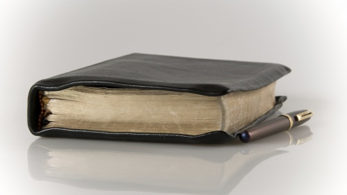 A Bible and pen laying on a table.