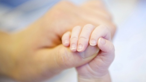 Uma pessoa segurando a mão de um bebê.