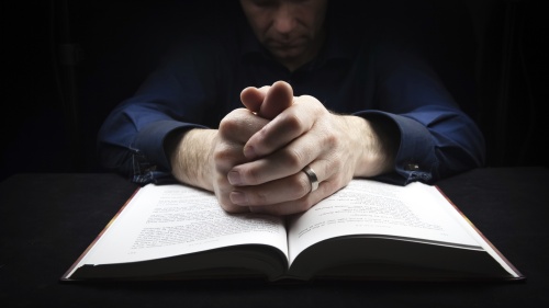 A person praying with a Bible.