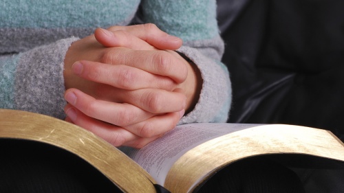 A person's hands on top of a Bible.