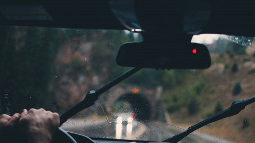 Um homem dirigindo um carro na chuva.