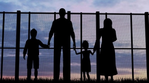 Uma família quatro olhando através de uma cerca alta.
