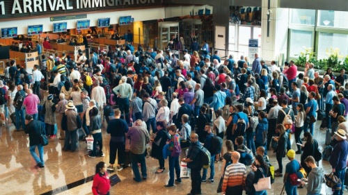 Viajantes em pé na fila do aeroporto para passar pela imigração e alfândega.