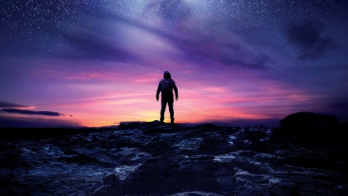 A silhueta dum homem olhando para o céu cheio de estrelas.