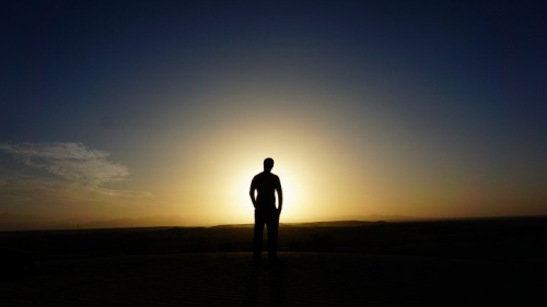 Um homem andando em um campo com os raios de sol brilhando sobre ele.