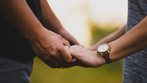 Foto de um homem e uma mulher comprometidos de mãos dadas.