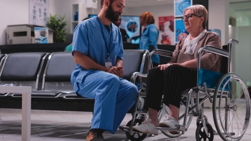 Um médico conversando com uma paciente em cadeira de rodas.