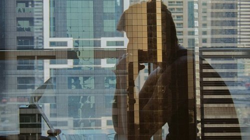 Reflexo de um homem pensativo enquanto olha para o computador.