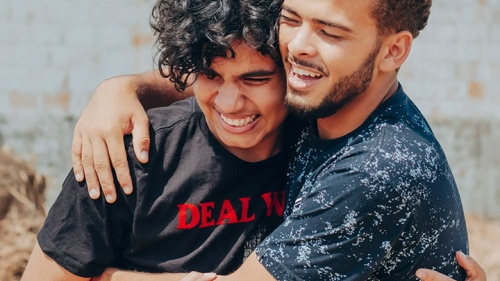 Caras felizes se abraçando casualmente.
