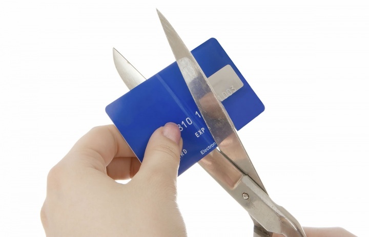 Uma pessoa cortando um cartão de crédito com uma tesoura.
