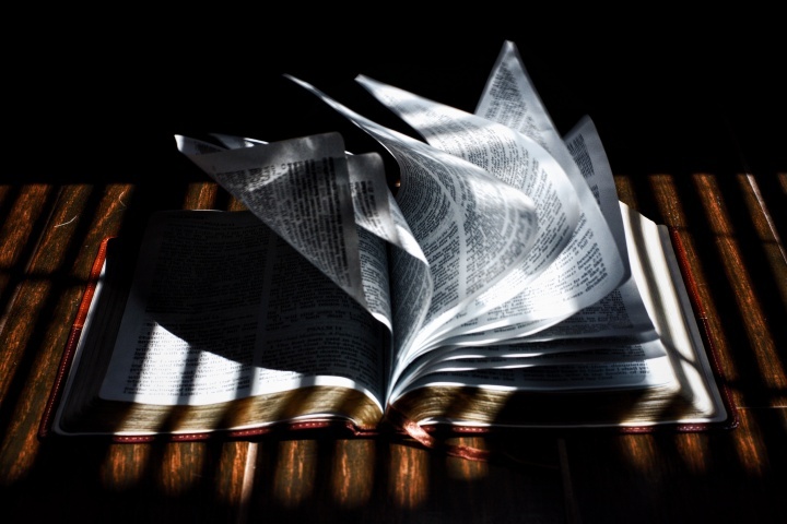 A Bíblia sobre uma mesa com suas páginas sopradas por uma brisa.