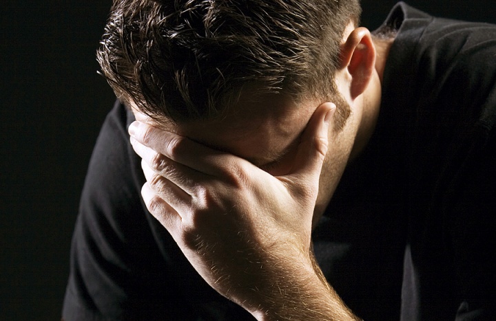 Um jovem segurando a cabeça com as mãos em tristeza ou remorso.