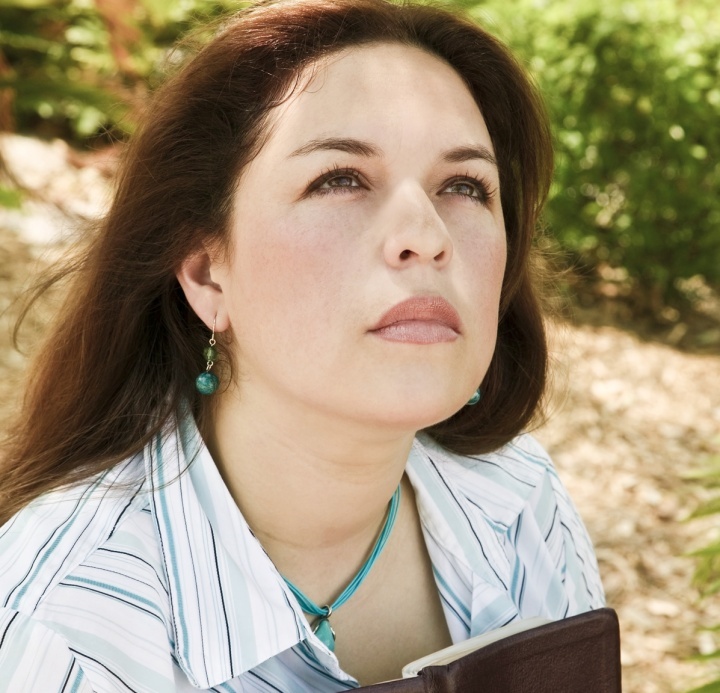 Uma mulher segurando uma Bíblia e olhando para cima.