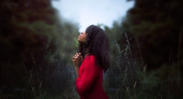 Uma jovem mulher orando em um campo.