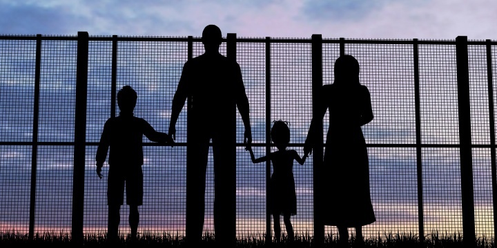Uma família quatro olhando através de uma cerca alta.