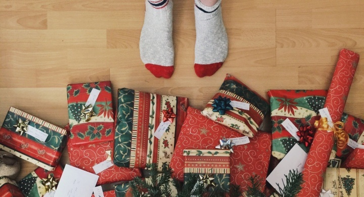 Uma pessoa com meias ao lado de presentes de Natal.