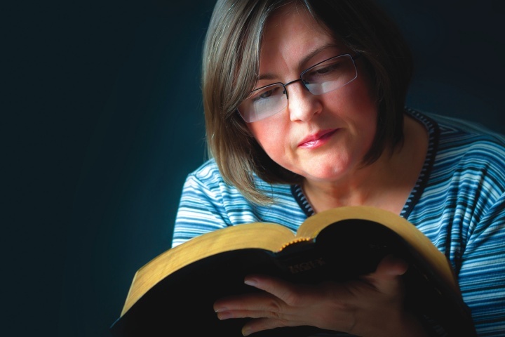 Uma mulher lendo uma Bíblia.