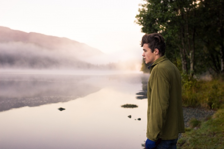 Um jovem olhando para um lago.
