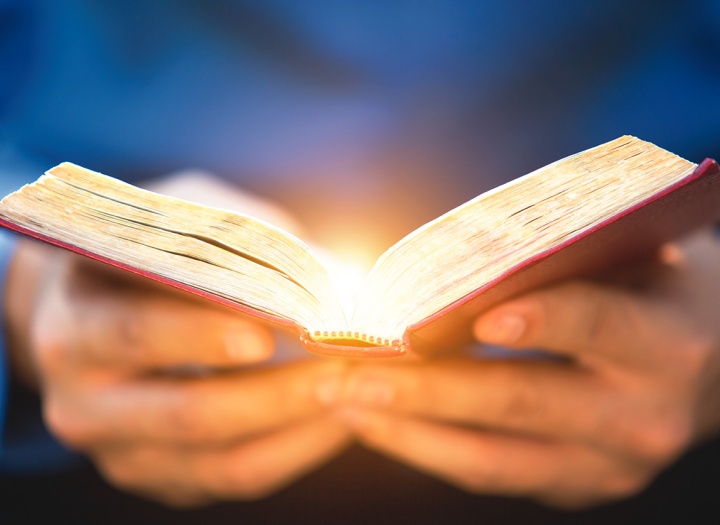 Uma Bíblia aberta com raios de luz.