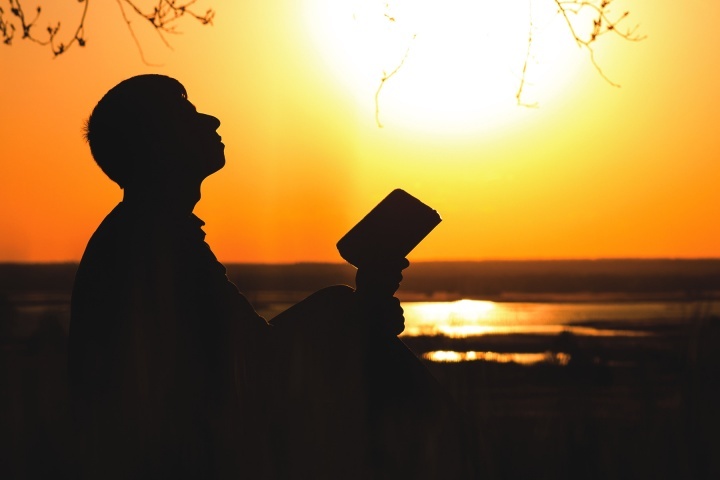 Uma pessoa segurando uma Bíblia e olhando para o céu.