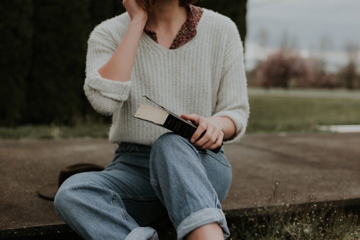 Uma mulher sentada em uma calçada segurando a Bíblia.