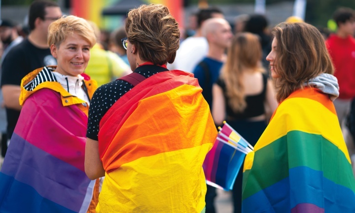 Pessoas enroladas em bandeiras LGBT.