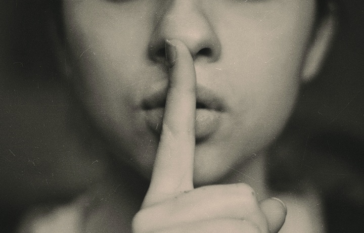 Foto de uma pessoa com o dedo nos lábios.