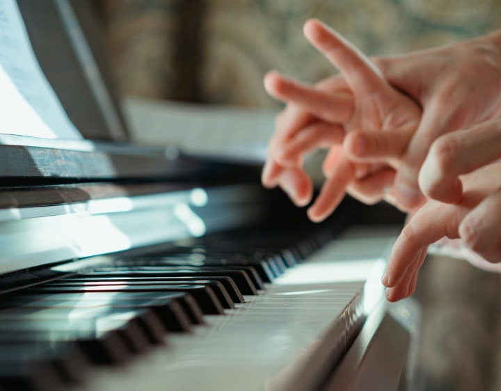 Um professor de piano guiando os dedos de uma criança no piano.