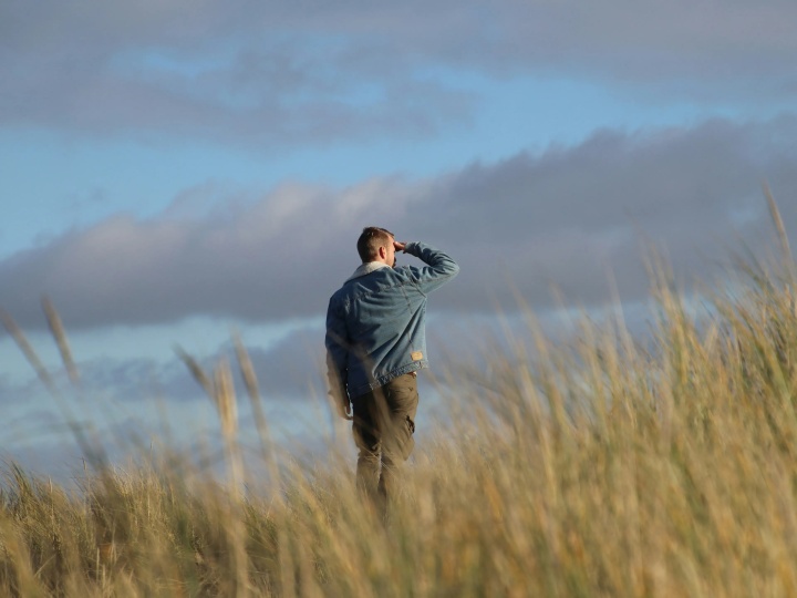 Um homem caminhando em um campo e olhando para as nuvens.Enquanto esses ventos da mudança no mundo geram incertezas, precisamos permanecer alertas aos eventos mundiais e reconhecer o chamado de Deus para preparar nossos corações para o que está por vir. Um homem caminhando em um campo e olhando para as nuvens.