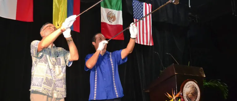 Men blowing horns against a backdrop of various countries' flags
