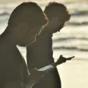 Dois homens olhando para seus celulares.