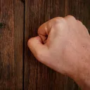 Um punho fechado batendo à porta.