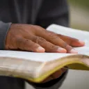 Um homem que segura uma Bíblia aberta.