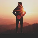 Uma pessoa de pé numa rocha com o sol atrás deles.