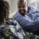 Um casal rindo e sentados juntos num sofá.