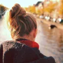 Uma mulher olhando para a água corrente perto duma ponte.