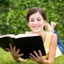 Uma mulher lendo uma Bíblia num campo de relva.