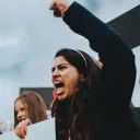 Uma mulher furiosa gritando com o punho no ar.