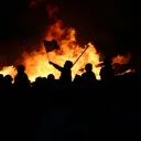 Pessoas em um tumulto queimando itens.