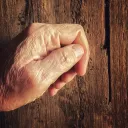 Um velho batendo numa velha porta de madeira.