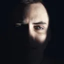 O rosto de um homem oculto nas sombras.