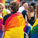 Pessoas enroladas em bandeiras LGBT.